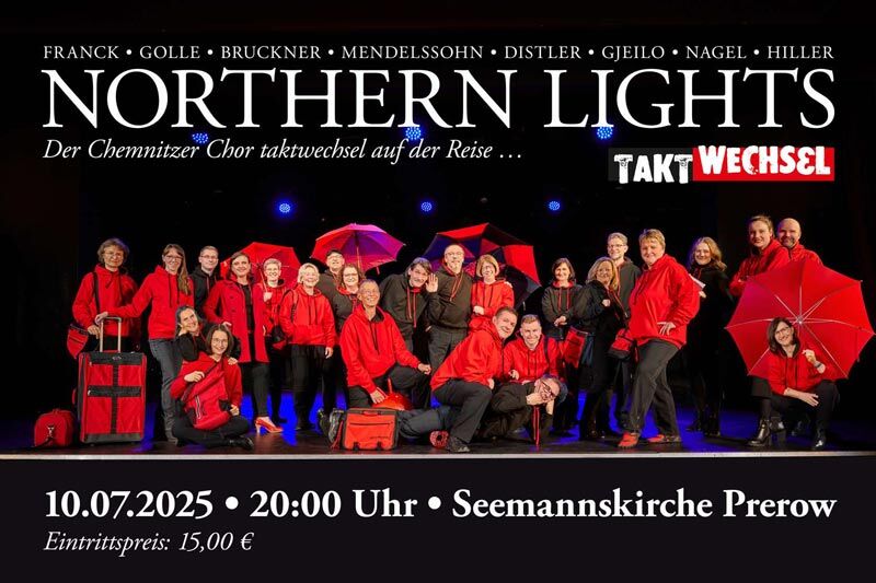 ein schwarz-rot gekleideter Chor steht auf einer ausgeleuchteten Bühne